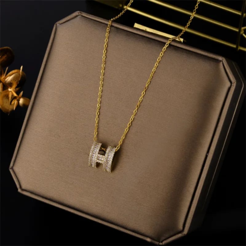 Hochwertige Edelstahl-Kette mit edlen, modernen goldenen Buchstaben H. Der H-Anhänger ist mit zahlreichen, winzigen Zirkonia-Steinen versehen. Stylisch und minimalistisch. Langlebig, wasserfest, hypoallergen und alltagstauglich.