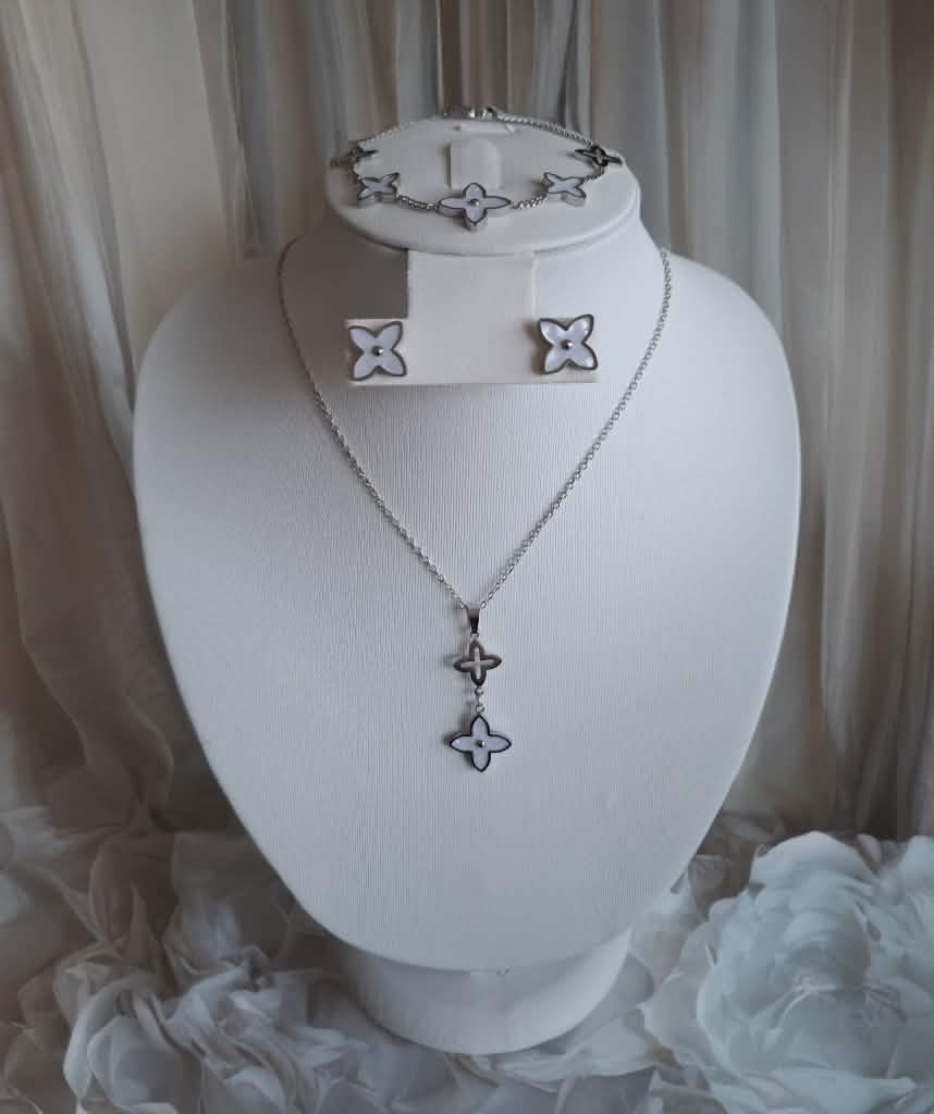 Hochwertiges Edelstahl-Set bestehend aus einer Kette, Armband und passenden Ohrsteckern in Weißgold. Femininer Stil mit strahlend weißen Blüten in Rautenform. Langlebig, wasserfest, hypoallergen und alltagstauglich.