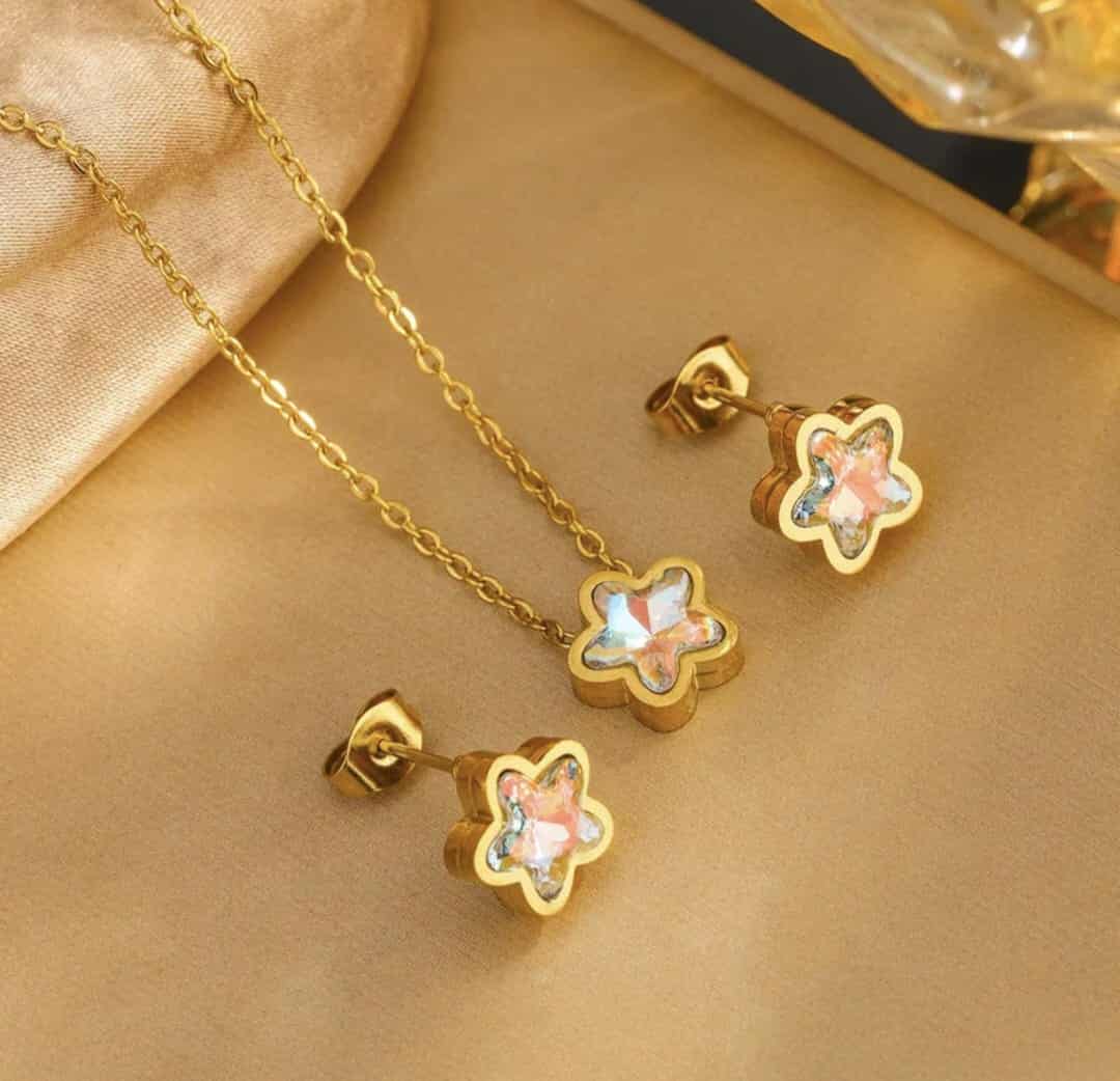 Hochwertiges Edelstahl-Set bestehend aus einer filigranen, goldenen Kette mit zartrosa Sternchen und passenden Ohrsteckern. Elegant und minimalistisch. Langlebig, wasserfest, hypoallergen und alltagstauglich.