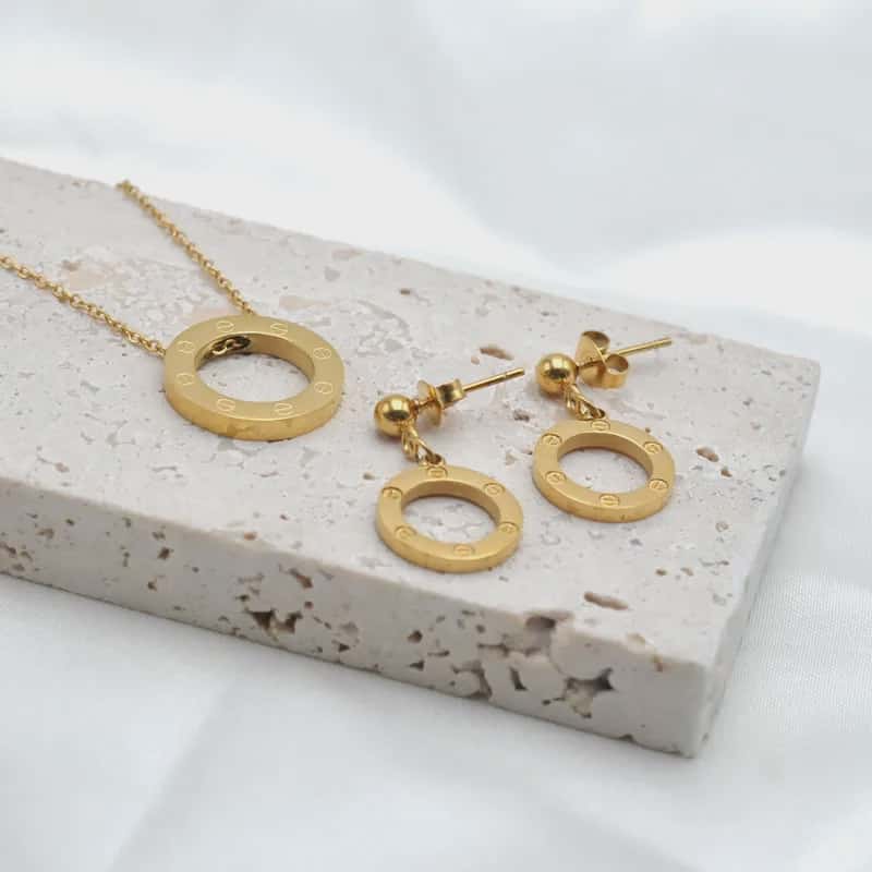Hochwertiges Edelstahl-Set bestehend aus einer edlen goldenen Kette und passenden Ohrhängern in runder Optik mit kreisförmiger Gravur. Minimalisch und feminin. Langlebig, wasserfest, hypoallergen und alltagstauglich.