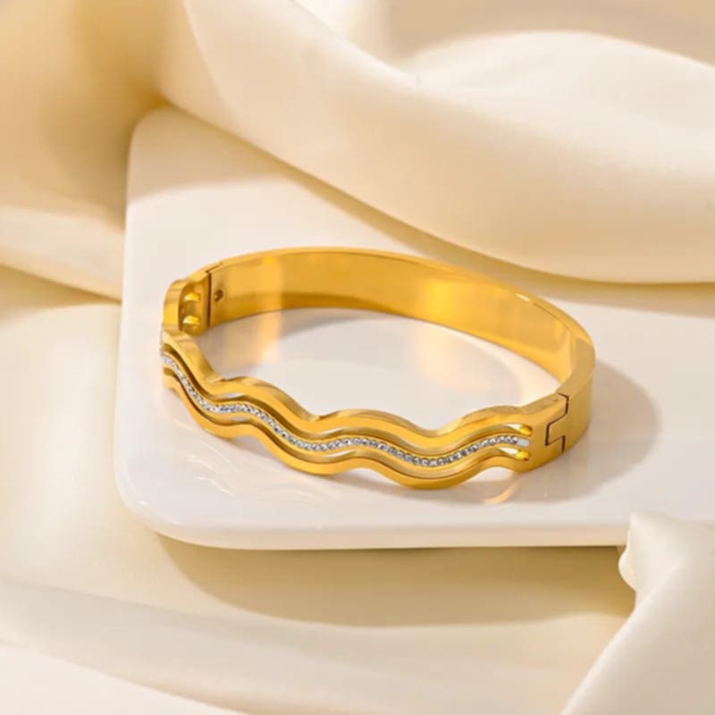 Hochwertiger Edelstahl Armreif in edlen, modernen, welligen Design mit feinen Zirkonia. In Gold oder Weißgold. Ein echtes Highlight am Handgelenk. Langlebig, wasserfest, hypoallergen und alltagstauglich.