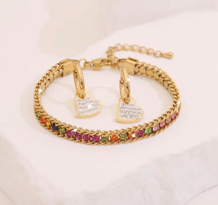 Hochwertiges Edelstahl-Set bestehend aus Creolen mit Anhänger und Armband in Gold. Femininer Stil mit zahlreichen, feinen bunten Zirkonia-Steinen. Langlebig, wasserfest, hypoallergen und alltagstauglich.