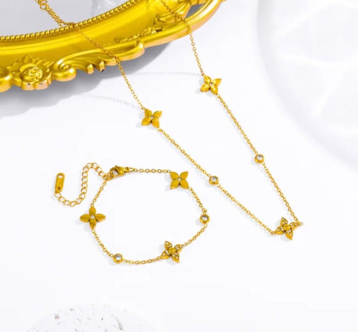 Hochwertiges Edelstahl-Set bestehend aus einer filigranen, goldenen Kette und passenden Armband. Femininer Stil mit zahlreichen, feinen Blüten in Rautenform mit Zirkonia-Steinen. Langlebig, wasserfest, hypoallergen und alltagstauglich.