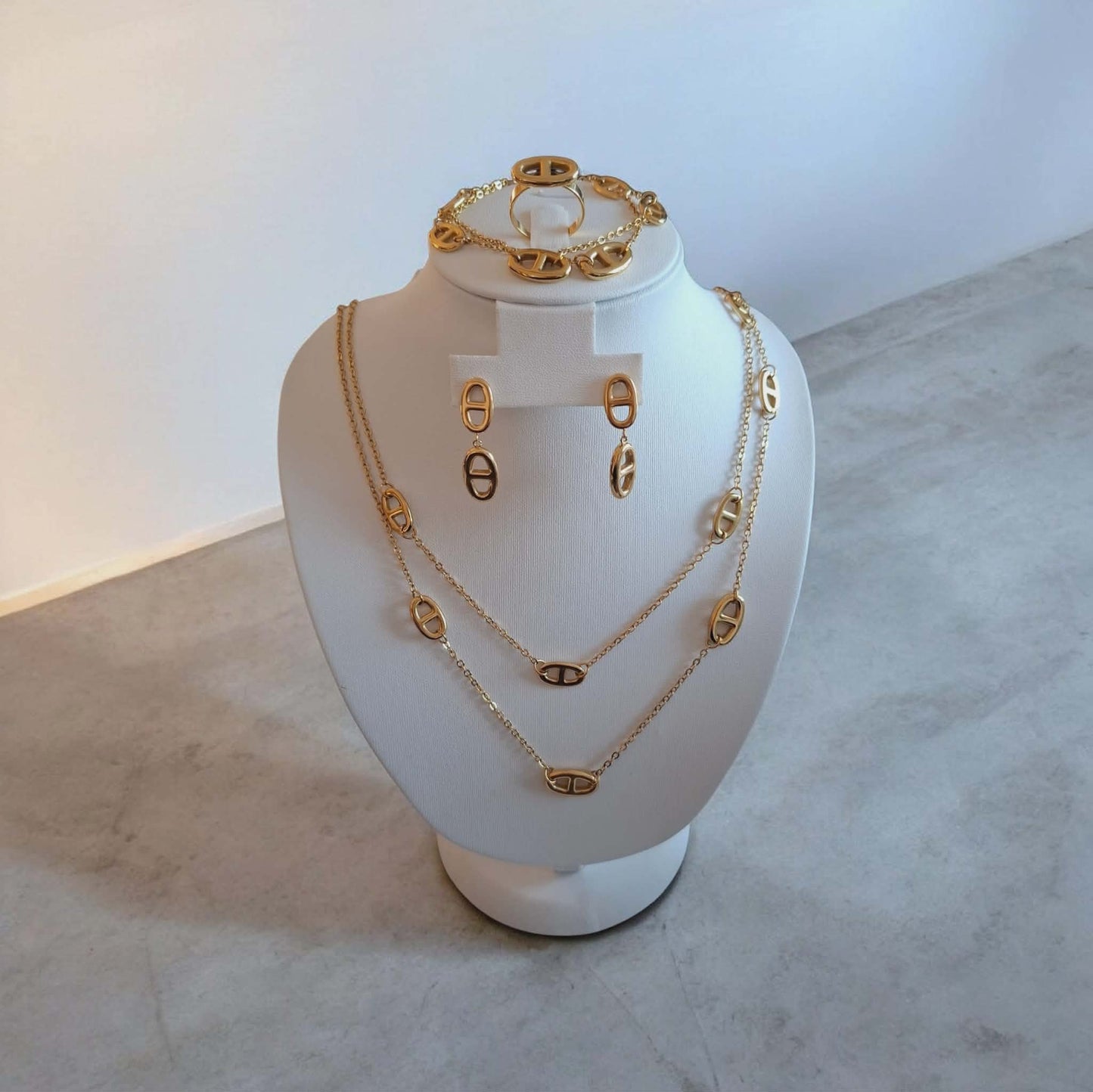 Hochwertiges vierteiliges Edelstahl-Set bestehend aus einer Kette passenden Ohrhängern, Armband und Ring in einer goldenen geometrischer Form. Langlebig, wasserfest, hypoallergen und alltagstauglich.