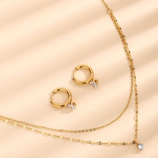 Hochwertiges Edelstahl-Set bestehend aus einer eleganten doppelreihigen Kette und feinen Creolen mit kleinem Zirkonia in edlen, goldenen, minimalistischen Stil. Langlebig, wasserfest, hypoallergen und alltagstauglich.